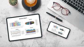 Tablet and smartphone with charts and reports on office desk workplace. Top view flat lay photo