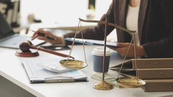 A woman in a business suit is holding a scale of justice in front of a desk with a video