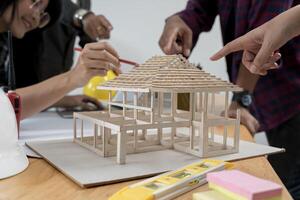 Group of an architect working and discussing about an architecture model together with shop drawing paper on table in office photo