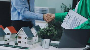 Two people shaking hands over a model of a house video