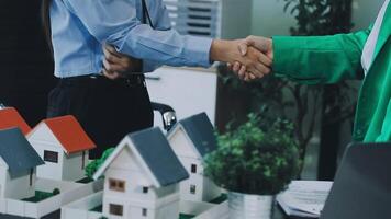Two people shaking hands over a model house video