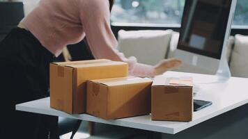A woman is working on her computer while holding a box video