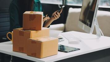 A woman is sitting at a desk with a laptop and a stack of boxes video