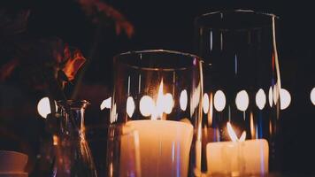 Candles and vases sit on a table with a candle in each video