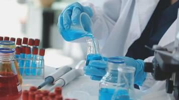A person in a lab coat is pouring liquid into a beaker video