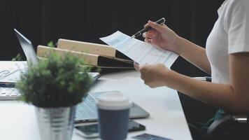 A woman is writing on a piece of paper while sitting at a desk video