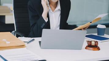 A woman in a business suit is sitting at a desk with a laptop and a folder video