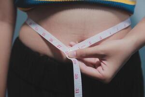 A woman is measuring her waist with a tape measure photo