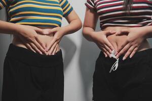 Two women with their hands on their stomachs photo