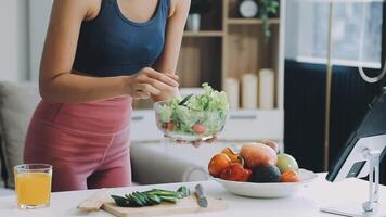 A woman is preparing a salad in front of a computer video