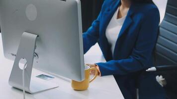 A woman in a blue suit sitting at a desk with a computer video