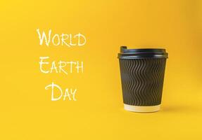 Coffee cup sits on a yellow background with the words World Earth Day photo