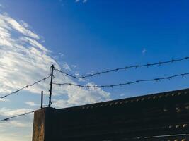 A fence with barbed wire is on a bridge photo