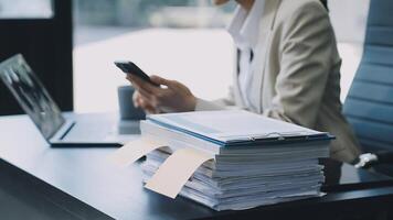 A woman in a business suit sitting at a desk with a stack of papers video