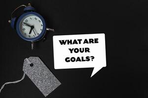 Clock is on a table with a tag that says What are your goals photo