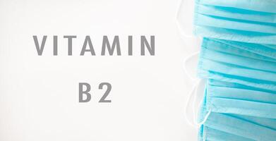 A blue stack of surgical masks with the word vitamin B2 written underneath photo