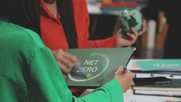 Two women are holding a tablet with the word net zero on it video
