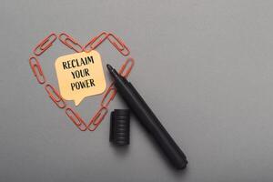 A black marker is on a gray surface with a heart shape made of paper clips photo