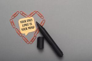 Black marker is on a gray surface with a heart made of paper clips photo