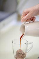 Icecream on a table with coffee being poured into it showing the texture and refreshing look of the drink, hand holding concept. photo