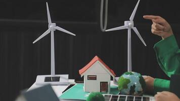 A person pointing at a wind turbine and a house video