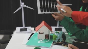 A man and woman are working on a model of a house with a solar panel video