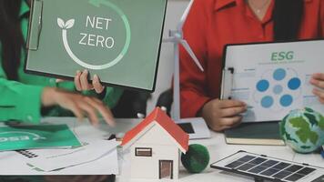 Two people sitting at a table with a net zero sign on it video
