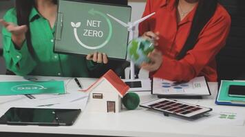 Two women sitting at a table with a net zero sign on it video