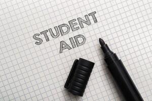 A marker is on a piece of paper with the word student aid written in marker photo