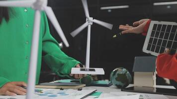 A woman is holding a wind turbine and a solar panel video