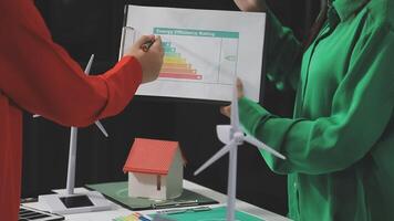 Two people holding a piece of paper with a house and wind turbines video