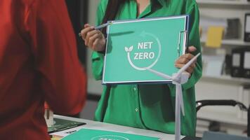 A woman holding a net zero sign in front of a table video