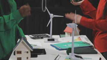 Two people standing around a table with wind turbines video