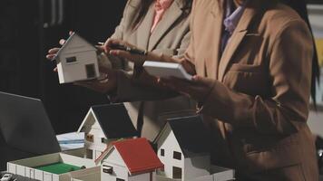 Two people are looking at model houses on a table video