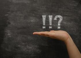 Hand is holding a chalkboard with a question mark and an exclamation point photo