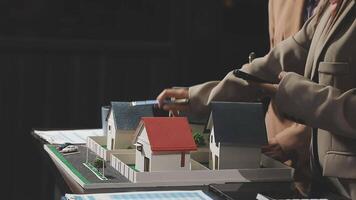A man and woman are looking at a model of a house video