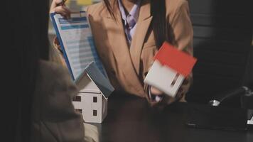 A woman is holding a house model and a piece of paper video