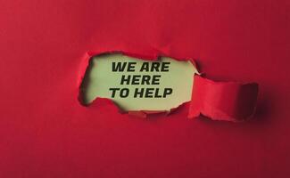 A red background with a torn piece of paper that says We are here to help photo