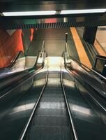 Long silver escalator with a red stripe down the middle photo