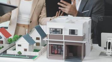 A man and woman are looking at a model of a house video