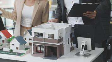 A man and woman are looking at a model of a house video
