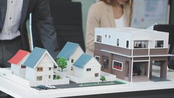 A man and woman are looking at a model of a house video