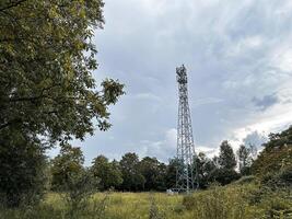 Tall tower is in the middle of a field with trees in the background photo