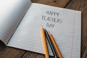 A notebook with pencils and the words Happy Teachers Day written on it photo