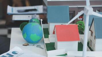 A model of a house with a wind turbine on top of it is on a table with papers video