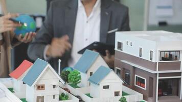 A man and woman are looking at a model of a house video