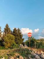 Red and white sign with a white line in the middle is on a hillside photo