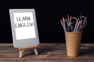 A white tablet with the word learn written on it is on a wooden table photo