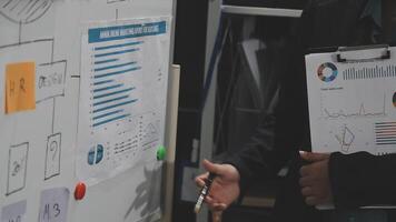 A man in a suit holding a clipboard with graphs and charts video