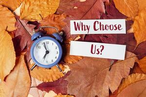Clock is on a pile of leaves with the words Why choose us photo